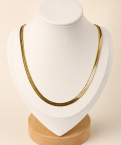 Cadena de acero quirúrgico dorado tipo snake chata de 40 cm, exhibida sobre busto blanco con fondo neutro cálido.