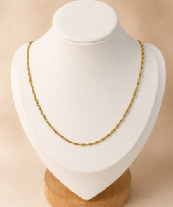 Cadena de acero quirúrgico dorado tipo Singapur fina de 40 cm, exhibida sobre busto blanco con fondo neutro cálido.