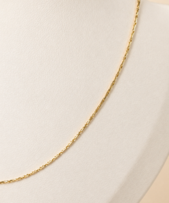 Cadena Dorada Sienna de acero quirúrgico exhibida sobre busto blanco con fondo neutro cálido mas de cerca.