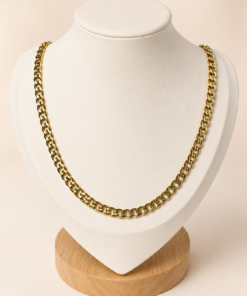 Cadena de acero quirúrgico dorado tipo cubana de 60 cm, exhibida sobre busto blanco con fondo neutro cálido.