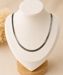 cadena snake de acero quirúrgico plateado sobre busto en fondo neutro cálido