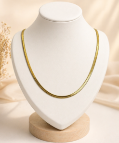 Cadena de acero quirúrgico dorado snake , exhibida sobre busto blanco con fondo neutro cálido