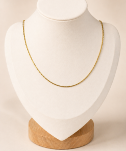 Cadena Dorada Sienna de acero quirúrgico exhibida sobre busto blanco con fondo neutro cálido.