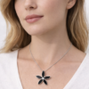 Modelo luciendo en su cuello cadena de plata 925 con dije de flor negra, diseño elegante y minimalista.