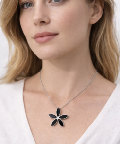 Modelo luciendo en su cuello cadena de plata 925 con dije de flor negra, diseño elegante y minimalista.