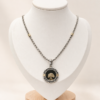 Conjunto en plata con cadena y dije circular Árbol de la Vida, con detalles en double de oro y fondo de resina negra.