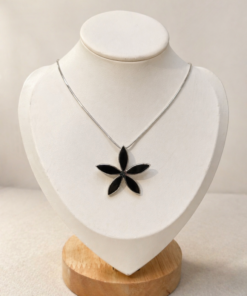 Cadena de plata 925 con dije de flor negra sobre busto blanco, diseño elegante y minimalista.