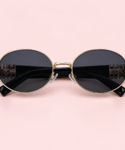 Lente de sol unisex LUMA ovalado con armazón dorado, cristales degradé negro y patillas negras.