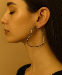 modelo de perfil exhibiendo caravanas aros con forma de corazon en acero quirurgico