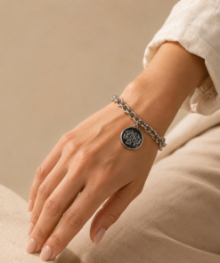 Pulsera de acero quirúrgico con cadena de eslabones y dije decorativo en acabado brillante. mano con pulsera