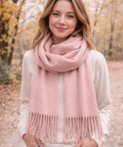 Modelo luciendo bufandón de tejido suave con flecos, ideal para looks abrigados de otoño e invierno, color rosa
