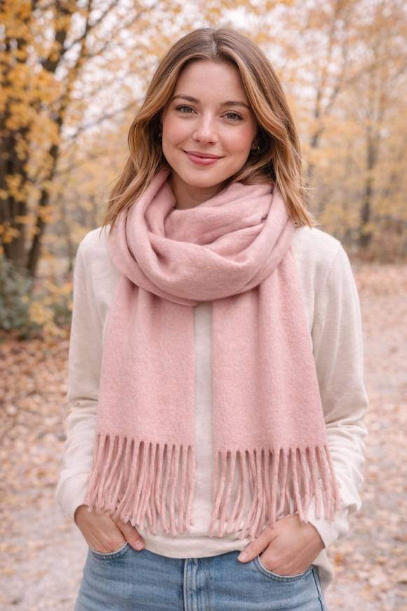 Modelo luciendo bufandón de tejido suave con flecos, ideal para looks abrigados de otoño e invierno, color rosa