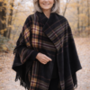 Modelo luciendo ruana polar escocesa negra con cuadros en tonos bordo, camel y beige