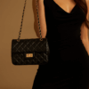 mujer de vestido negro con cartera glam negra, cadena y broche en uruguay