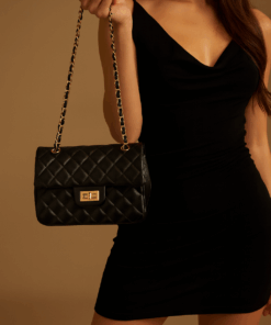 mujer de vestido negro con cartera glam negra, cadena y broche en uruguay