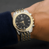 mano de hombre exhibiendo reloj combinado plateado con dorado fondo negro