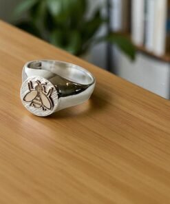 anillo plata con aplique en oro de abeja sobre una mesa