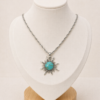 Conjunto en plata 925 con cadena fina 45cm y dije de sol con piedra turquesa, presentado sobre busto blanco.