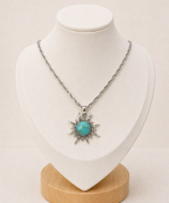 Conjunto en plata 925 con cadena fina 45cm y dije de sol con piedra turquesa, presentado sobre busto blanco.