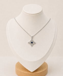 Cadena fina con dije celta calado y piedra azul central, presentada sobre busto blanco.