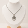 Conjunto en plata 925 con cadena fina y dije ovalado calado Árbol de la Vida, presentado sobre busto blanco con fondo neutro cálido.