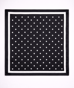 Pañuelo de seda con estampado de lunares y borde definido negro, sobre fondo neutro claro