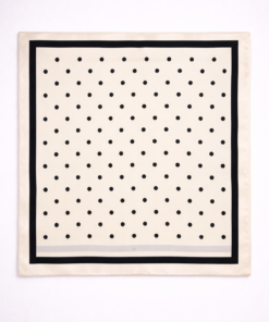 Pañuelo de seda con estampado de lunares y borde definido beige, sobre fondo neutro claro