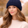 Gorro tejido con pompon de piel sintética en modelo mujer con fondo otoñal claro