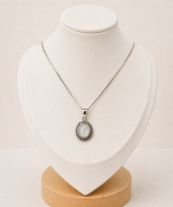 Cadena de plata 925 con dije ovalado de nácar, presentada sobre busto blanco con fondo neutro cálido.