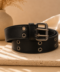 Cinto de cuero sintético de 4 cm con doble ojalillo metálico y hebilla doble pasador sobre fondo beige elegante negro