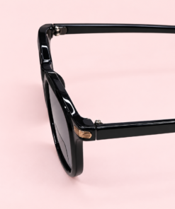 Lente de sol unisex NOA redondeado con armazón negra cristales negros y detalles metálicos dorados de perfil