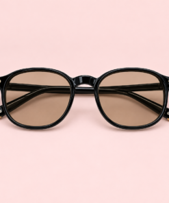 Lente de sol unisex NOA redondeado con armazón negro, cristales transparentes beige y detalles metálicos dorados
